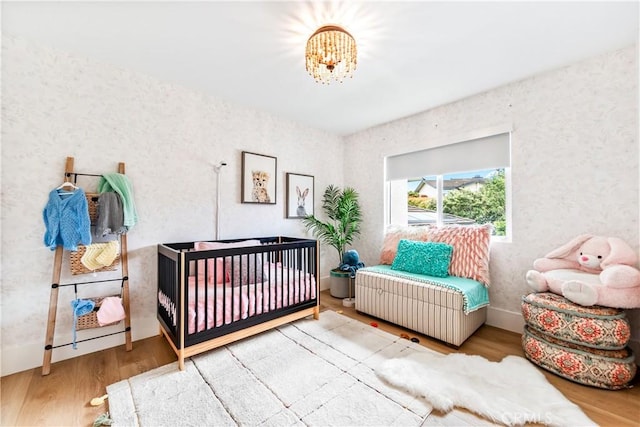 9 Jasmine Creek Dr, Corona Del Mar, CA 92625 - bedroom featuring wood finished floors, a nursery area, a chandelier, and wallpapered walls