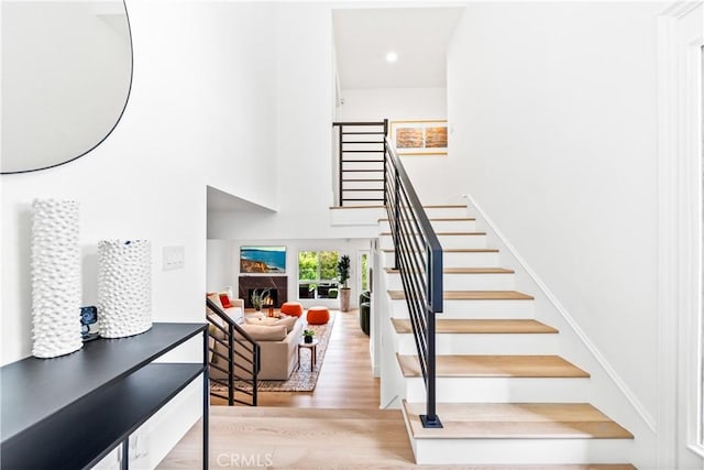 9 Jasmine Creek Dr, Corona Del Mar, CA 92625 - stairway with wood finished floors, a towering ceiling, a lit fireplace, and recessed lighting