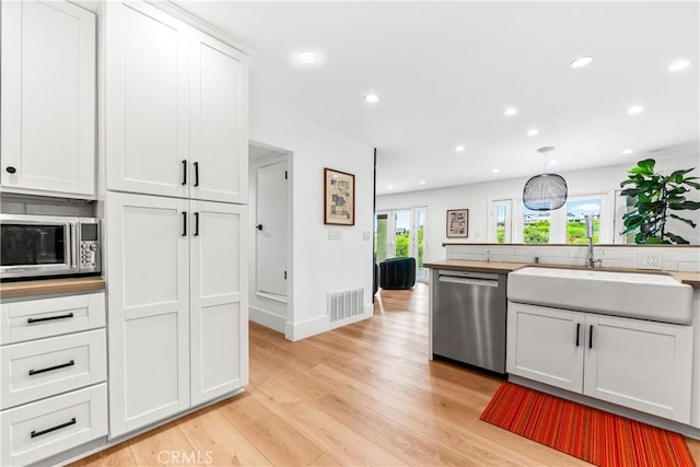 9 Jasmine Creek Dr, Corona Del Mar, CA 92625 - kitchen with stainless steel appliances, a sink, light wood-style floors, recessed lighting, and white cabinets