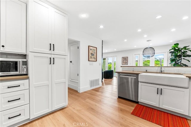 9 Jasmine Creek Dr, Corona Del Mar, CA 92625 - kitchen with appliances with stainless steel finishes, light wood finished floors, recessed lighting, and white cabinetry