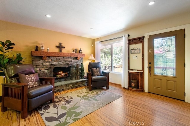 23697 Bowl Rd, Crestline, CA 92325 - living area featuring a stone fireplace, recessed lighting, plenty of natural light, and wood finished floors