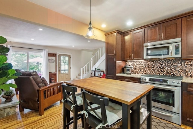 23697 Bowl Rd, Crestline, CA 92325 - kitchen with appliances with stainless steel finishes, decorative backsplash, open floor plan, and light wood-type flooring