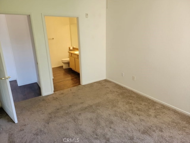 unfurnished bedroom featuring baseboards, carpet flooring, and ensuite bath