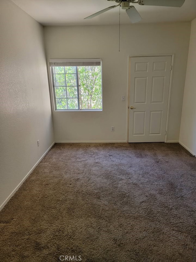 carpeted empty room with a ceiling fan and baseboards