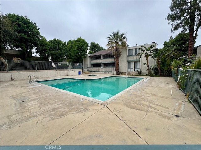 pool with a patio area and fence