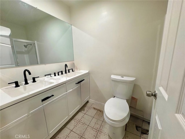 bathroom with double vanity, toilet, a stall shower, and a sink