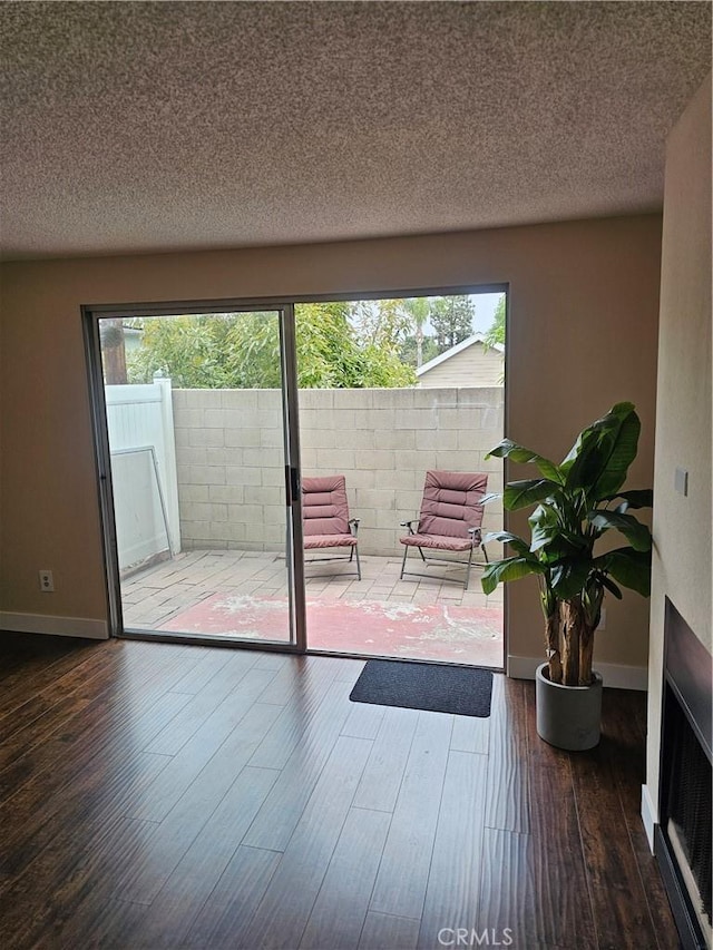 entryway with a textured ceiling, baseboards, and wood finished floors