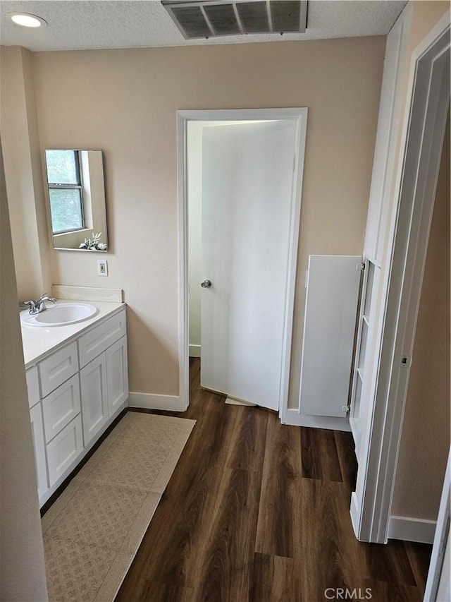 bathroom featuring baseboards, vanity, visible vents, and wood finished floors