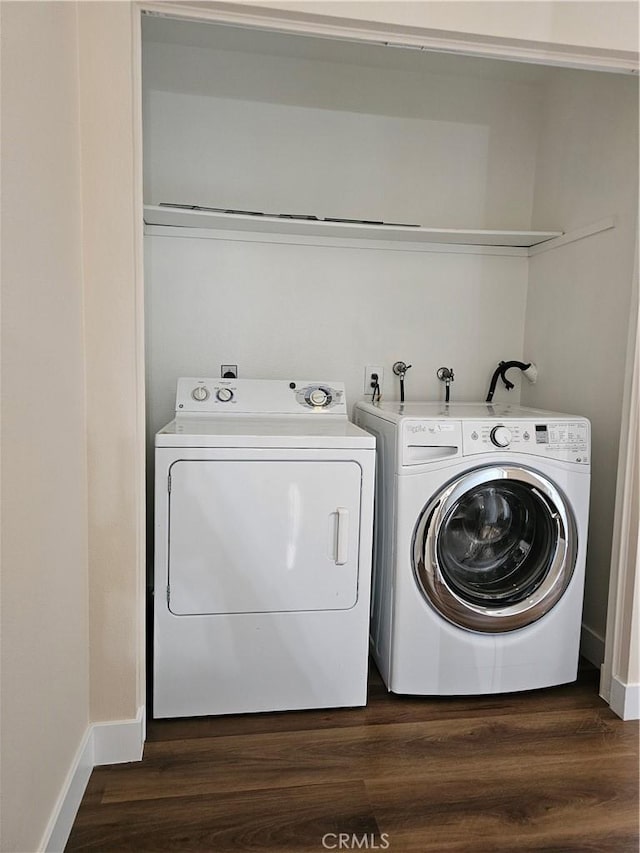 laundry area with washing machine and clothes dryer, baseboards, and dark wood-type flooring