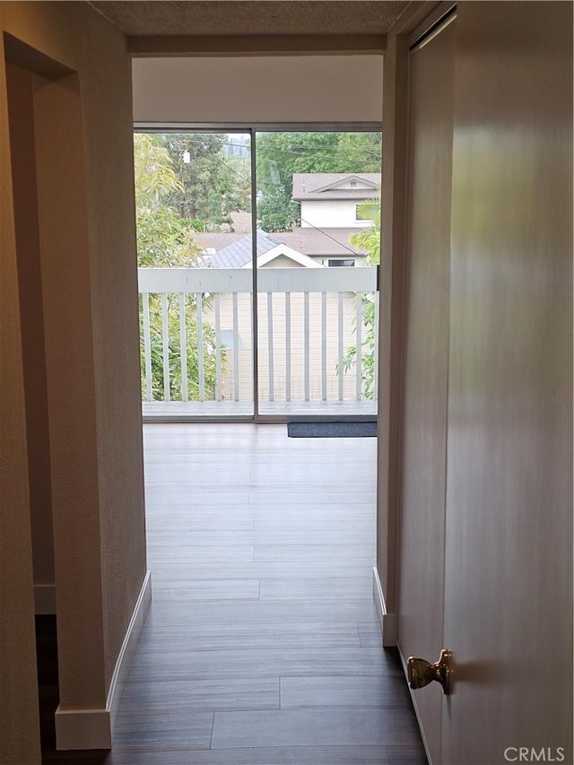 corridor with baseboards and wood finished floors
