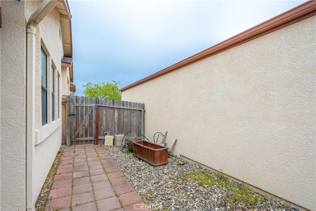 view of home's exterior with stucco siding, a gate, and fence