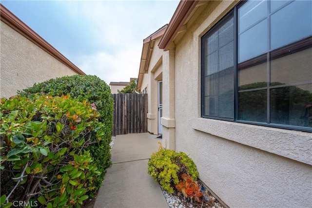 view of side of home with fence and stucco siding