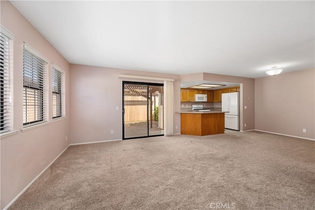 unfurnished living room with light carpet and baseboards