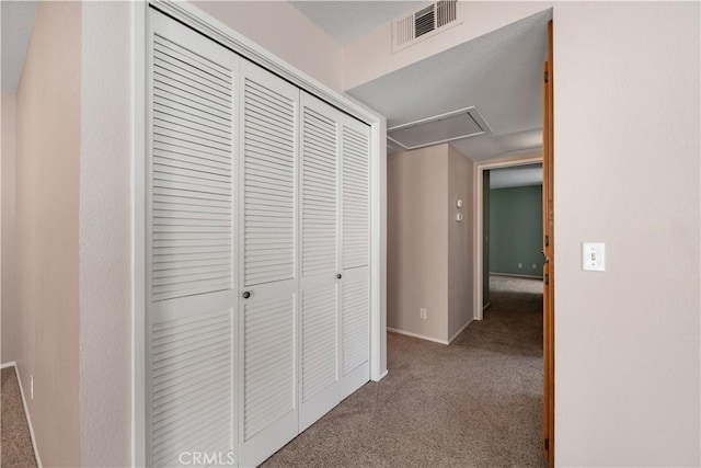 hall featuring attic access, carpet floors, baseboards, and visible vents