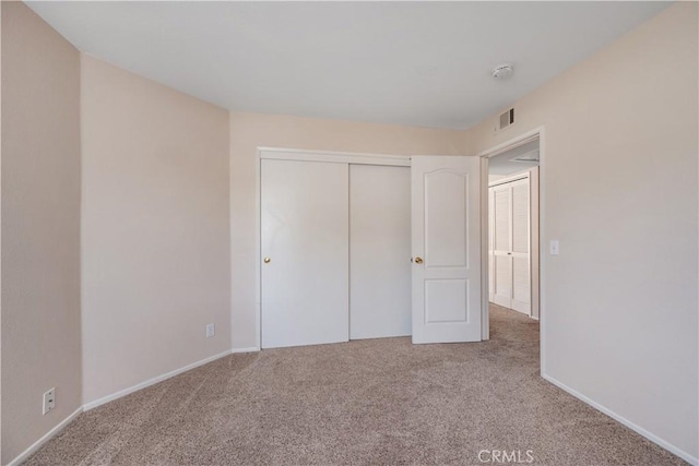 unfurnished bedroom with baseboards, a closet, visible vents, and carpet floors