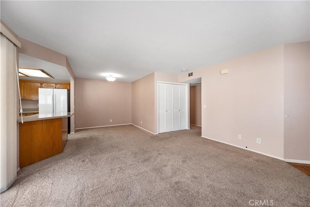 unfurnished living room with light carpet and baseboards
