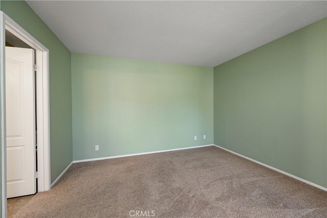 spare room featuring baseboards and carpet
