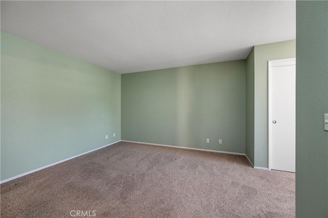 spare room with baseboards and carpet