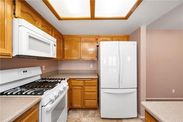 kitchen featuring white appliances, light countertops, and brown cabinets
