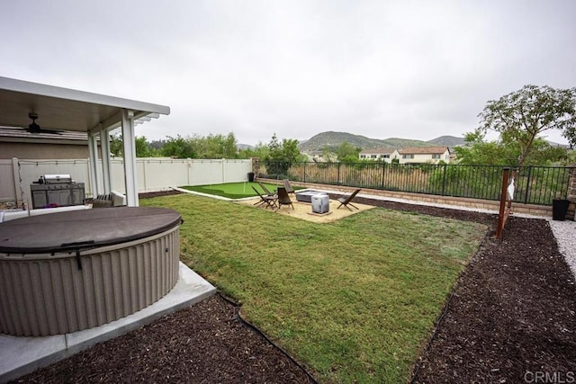 view of yard with a hot tub, ceiling fan, and a mountain view