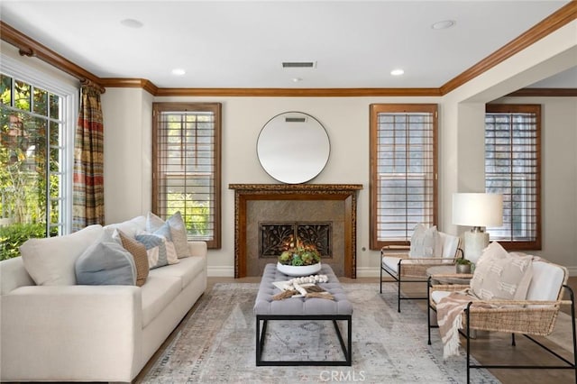 living area featuring a lit fireplace, crown molding, a wealth of natural light, and visible vents