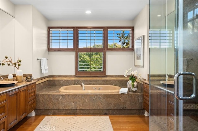 full bathroom with a garden tub, vanity, and wood finished floors