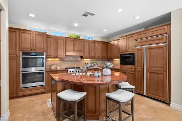 kitchen with built in appliances, tasteful backsplash, visible vents, and a sink