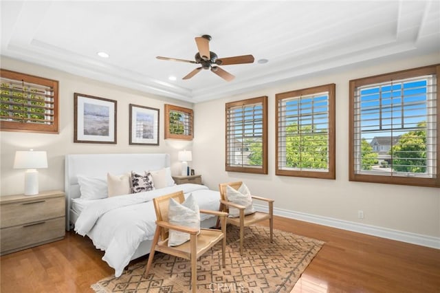 bedroom featuring a tray ceiling, recessed lighting, baseboards, ceiling fan, and wood finished floors