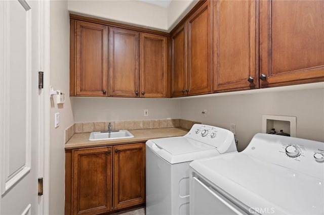 clothes washing area featuring a sink, cabinet space, and washer and dryer
