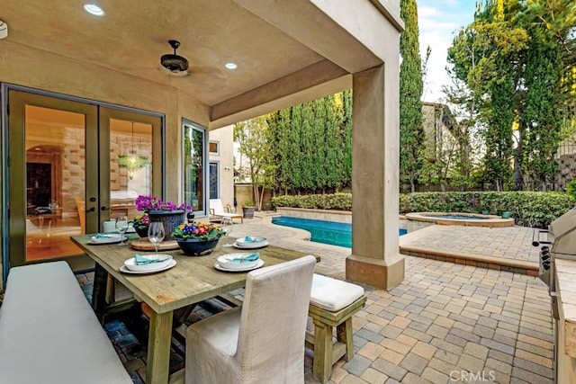 view of patio with outdoor dining area, an in ground hot tub, a fenced backyard, and a fenced in pool