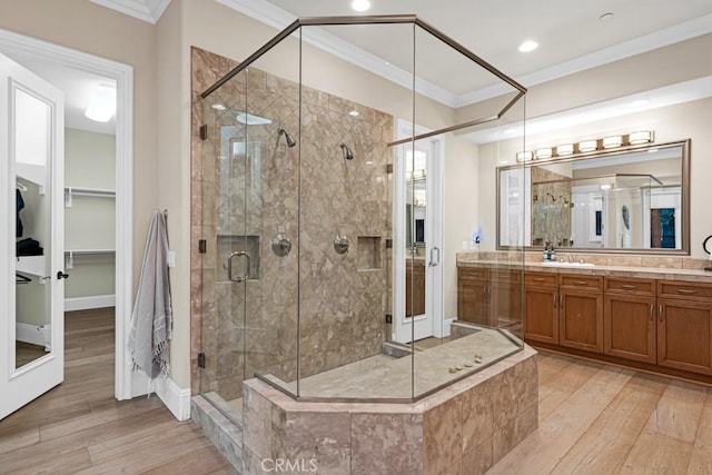 full bathroom with vanity, ornamental molding, a shower stall, and wood finished floors