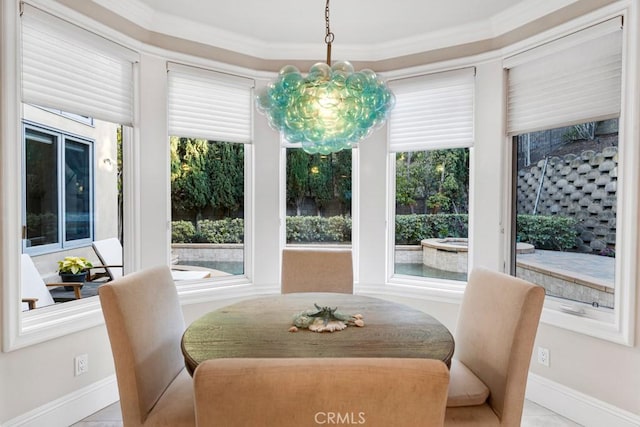 dining area featuring baseboards, ornamental molding, and a notable chandelier
