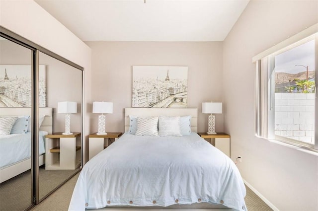 carpeted bedroom featuring a closet and baseboards