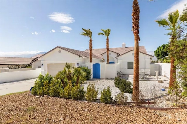 view of front of home featuring an attached garage, a tiled roof, stucco siding, a chimney, and fence private yard
