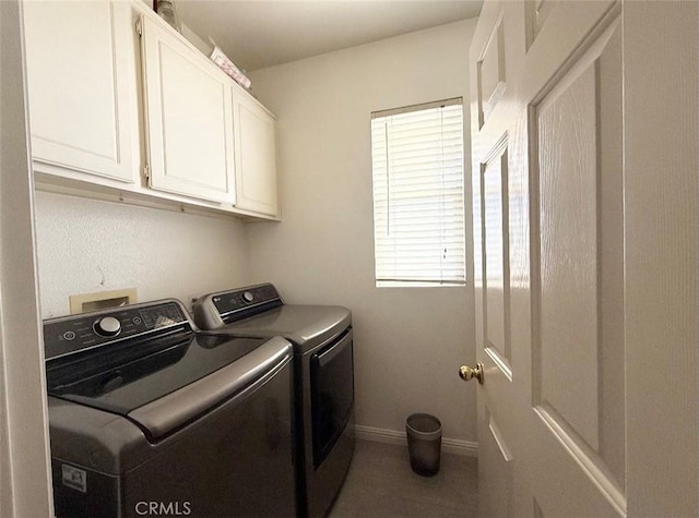 washroom featuring baseboards, washer and dryer, and cabinet space