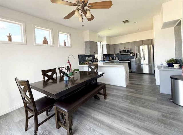 dining area with a ceiling fan, a wealth of natural light, visible vents, and wood finished floors