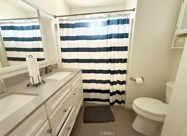 full bathroom featuring toilet, a shower with curtain, double vanity, and a sink