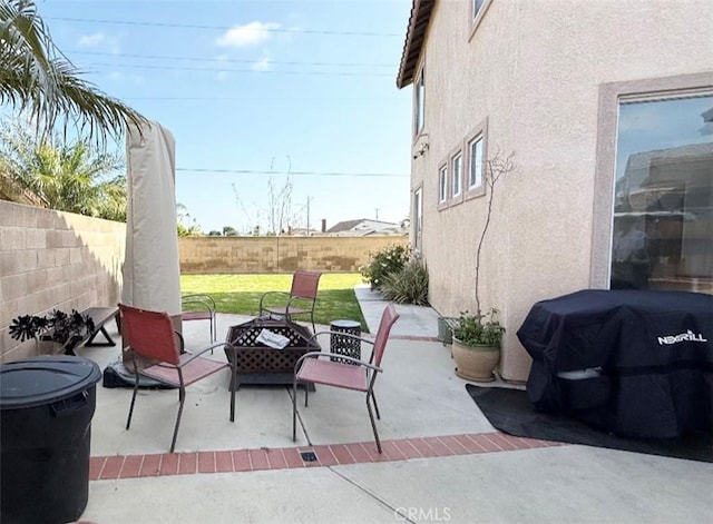 view of patio featuring a fenced backyard, an outdoor fire pit, and area for grilling