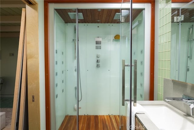 full bath featuring a sink, a shower stall, visible vents, and wood finished floors