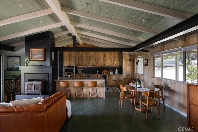 dining room with finished concrete floors, wooden ceiling, wood walls, and vaulted ceiling with beams