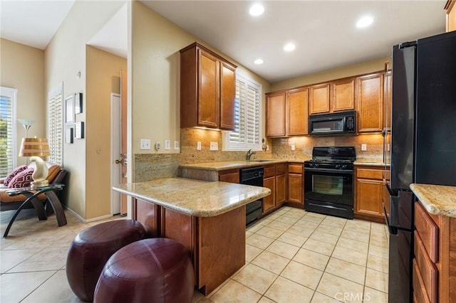 79260 Cool Reflection Ln, Quinta, CA 92253 - kitchen with black appliances, a peninsula, a sink, brown cabinets, and light tile patterned flooring