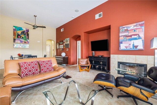 79260 Cool Reflection Ln, Quinta, CA 92253 - tiled living room with arched walkways, a high ceiling, a ceiling fan, and a tile fireplace