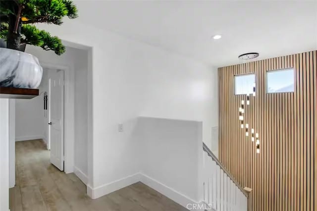 hall featuring recessed lighting, baseboards, an upstairs landing, and light wood-style floors