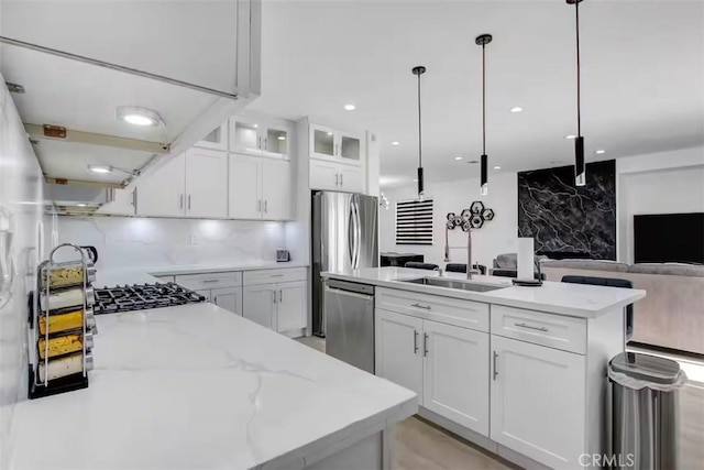 kitchen featuring white cabinetry, stainless steel appliances, open floor plan, and a sink