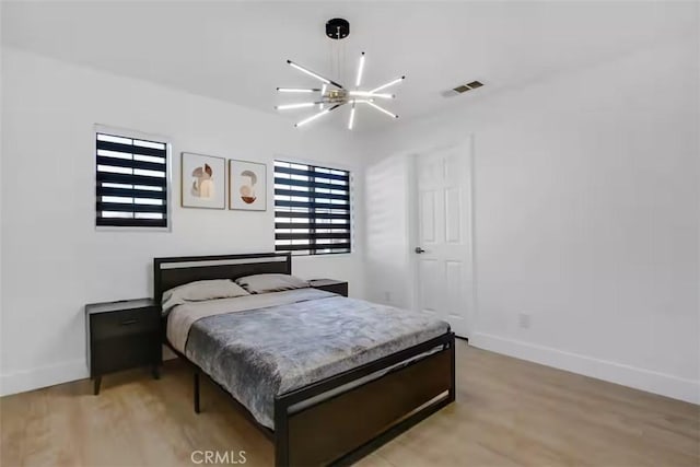 bedroom featuring baseboards, an inviting chandelier, light wood-type flooring, and visible vents