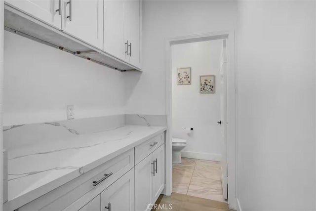bathroom with vanity, toilet, baseboards, and marble finish floor