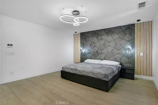 bedroom featuring an inviting chandelier, baseboards, visible vents, and wood finished floors