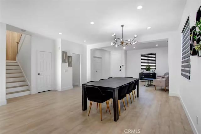 dining space with a notable chandelier, light wood-type flooring, baseboards, and stairs