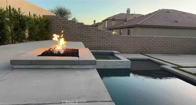 43118 Fiore St, Indio, CA 92203 - pool at dusk featuring a fenced backyard, a fenced in pool, and a fire pit