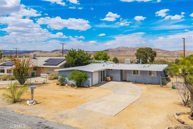 ranch-style home featuring driveway, stucco siding, a mountain view, and fence